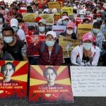 Manifestantes exhiben pancartas con fotografías de Aung San Suu Kyi y un cartel del "Movimiento de desobediencia civil" para protestar contra el golpe militar en Yangon
