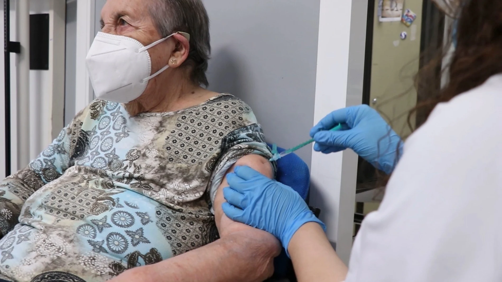 Una sanitaria inyecta la vacuna a una mujer mayor en Valencia