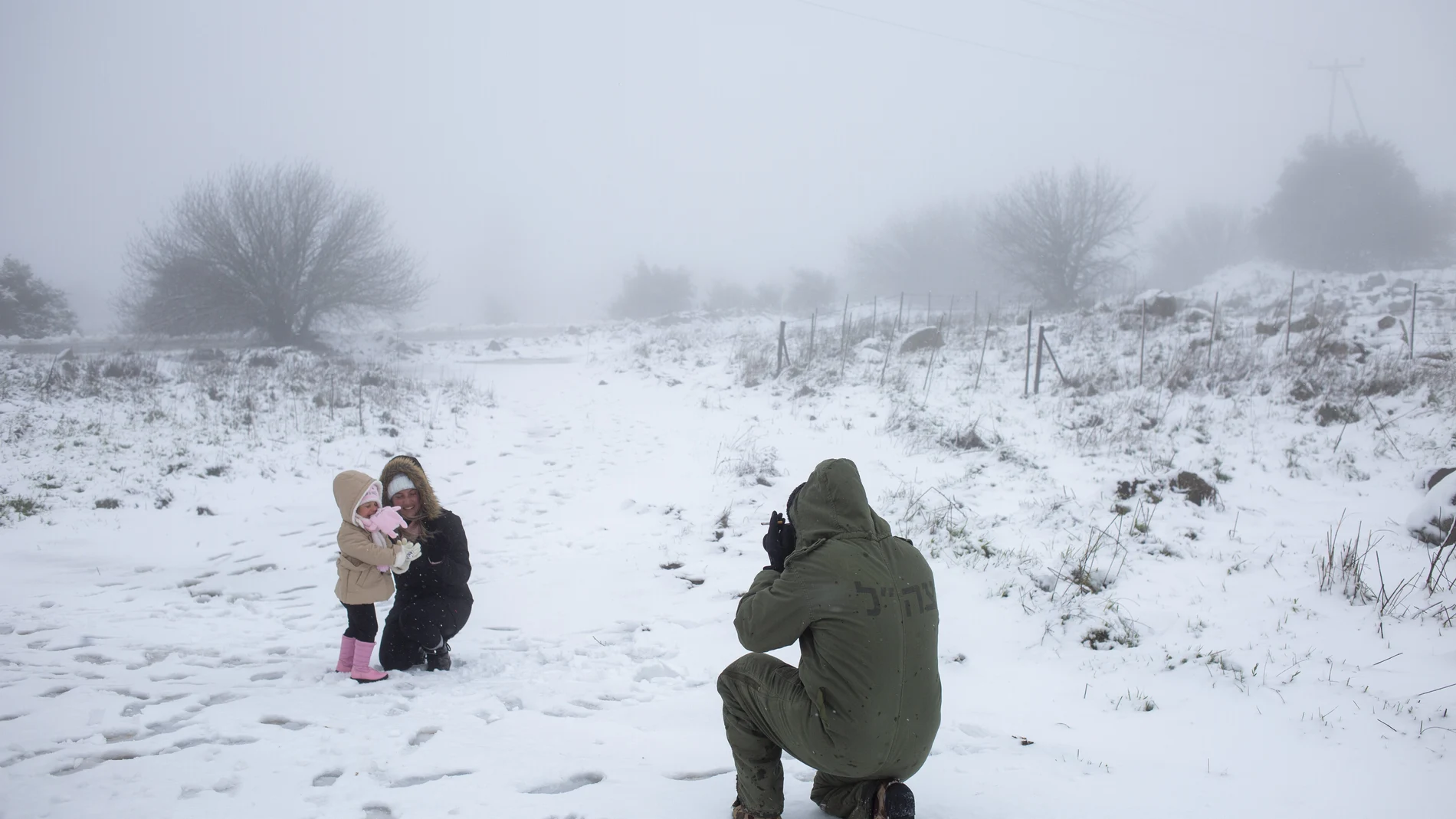 Un soldado israelí hace fotos a su familia en la nieve cerca de la frontera con Siria en los Altos del Golán, este miércoles