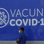 Un hombre camina frente a un anuncio de vacuna contra la covid-19 en San Salvador.