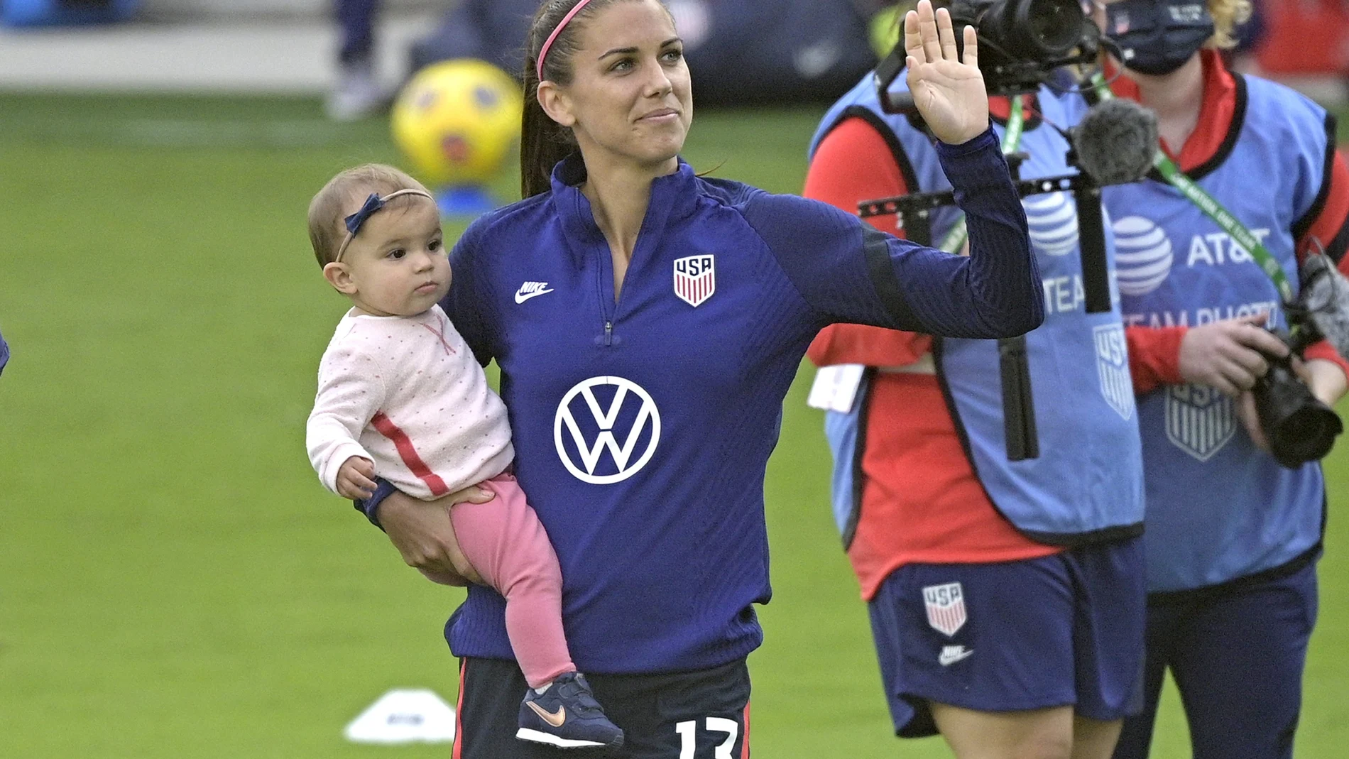 United States forward Alex Morgan (13) waves to fans in the stands while holding her daughter Charlie Elena Carrasco after a SheBelieves Cup women's soccer match against Brazil, Sunday, Feb. 21, 2021, in Orlando, Fla. (AP Photo/Phelan M. Ebenhack)