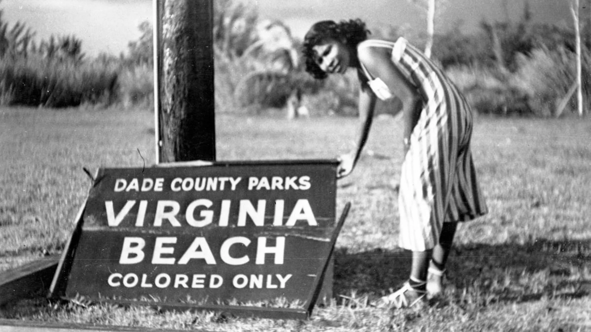 Fotografía de los años 40 cedida por el Parque Histórico de Virginia Key Beach donde aparece una mujer señalando un cartel que dice "Solo para gente de color" derribado por un huracán en la segregada playa de Virginia en la Bahía Vizcaína, en Miami