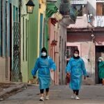 Trabajadoras de la salud recorren una calle cerrada por la pandemia, en La Habana (Cuba)