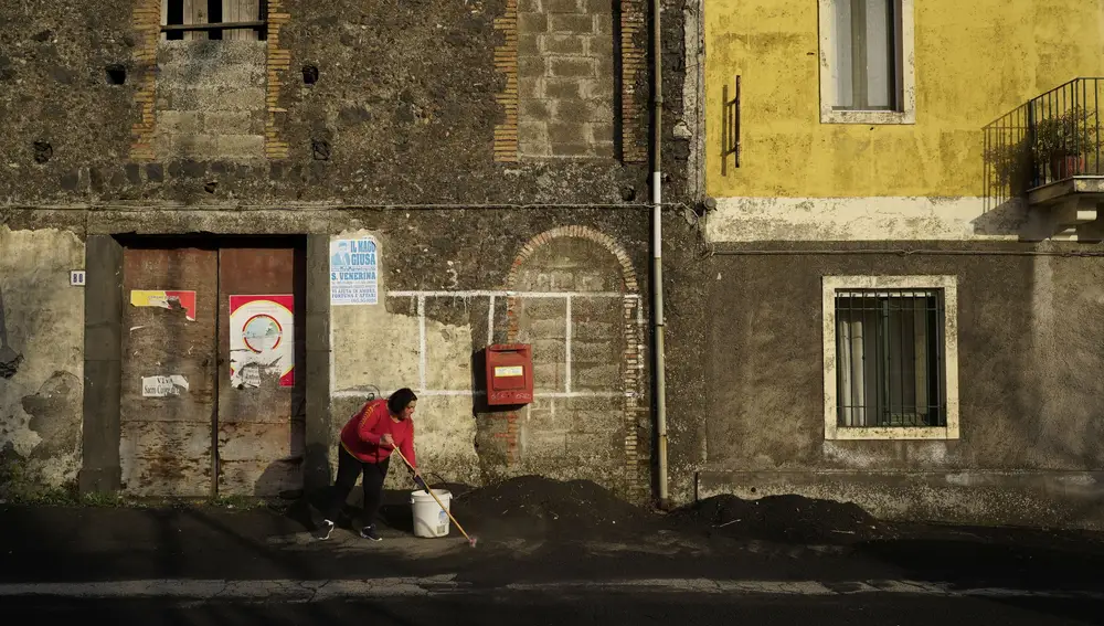 Una mujer barre las cenizas del Etna en Fornazzo