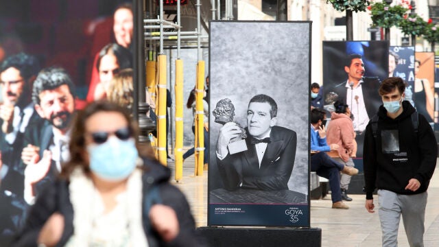 Varias personas pasean por calle Larios, donde ha sido inaugurada la exposición de fotografías con motivo de la celebración en Málaga de los Goya