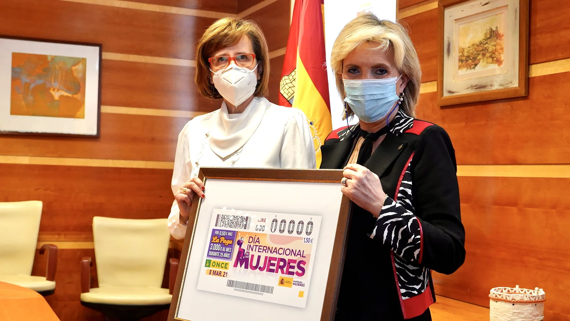 La consejera de Sanidad, Verónica Casado, recibe de la presidenta de la Once en Castilla y León, Rosa María Rubio Lázaro, un cupón conmemorativo con motivo del 8M