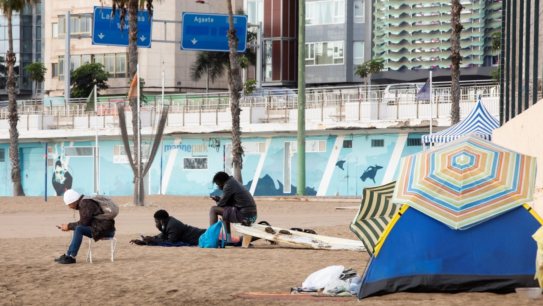 Tres inmigrantes descansan en la playa de las Alcaravaneras, en Las Palmas de Gran Canaria