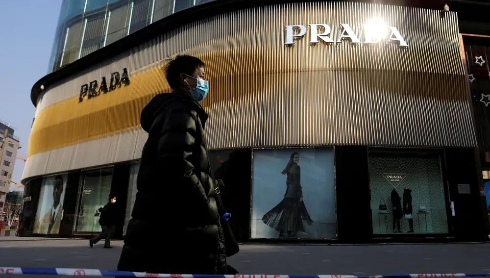 FILE PHOTO: A man wearing a face mask following the coronavirus disease (COVID-19) outbreak walks past a store of Italian luxury brand Prada on a shopping street in Beijing, China, January 20, 2021. REUTERS/Tingshu Wang/File Photo GLOBAL BUSINESS WEEK AHEAD