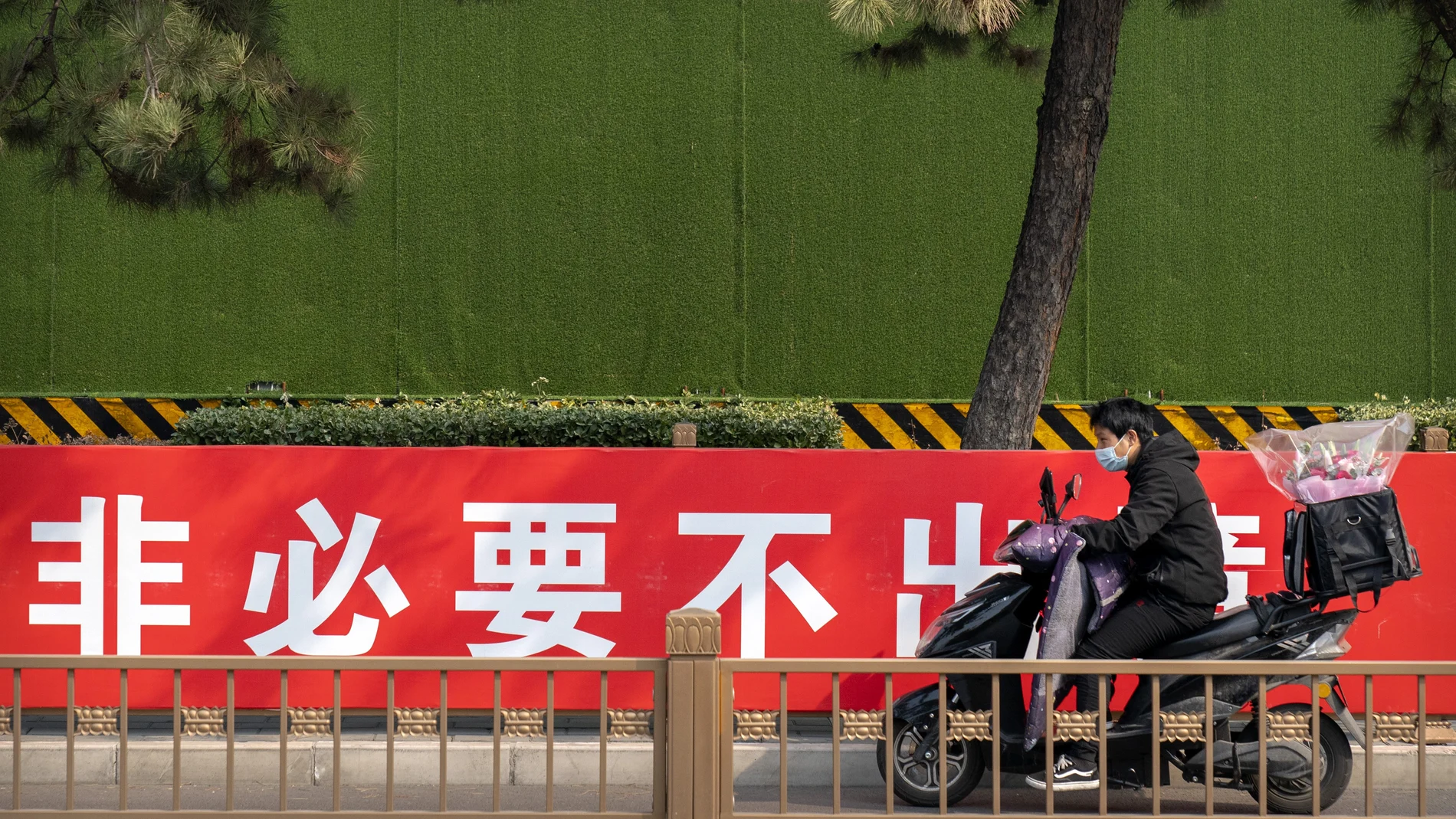 Un hombre con una moto en una calle de Pekín