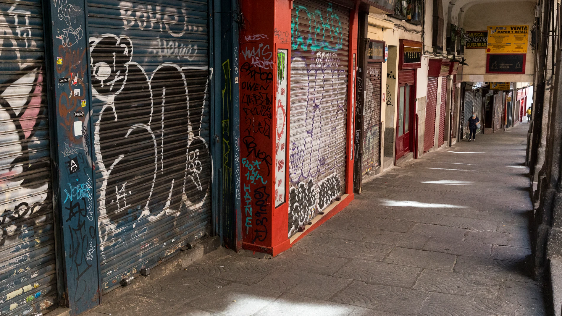 Una mujer pasea por la hilera de comercios cerrados en Madrid por la crisis económica
