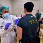 Una trabajadora sanitaria suministra la vacuna contra el Covid-19 a un agente de la Guardia Civil de Cartagena en el pabellón deportivo del Polígono Cabezo Beata de Cartagena,