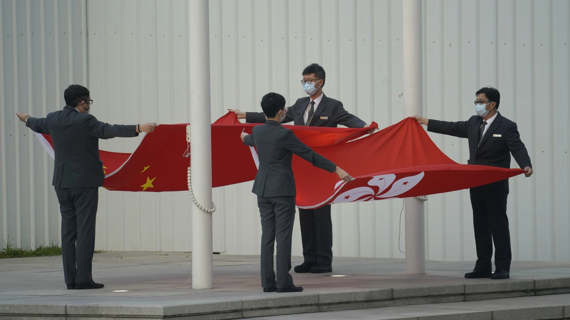 Miembros del personal doblan las banderas de China y Hong Kong en el Consejo Legislativo en Hong Kong, hoy