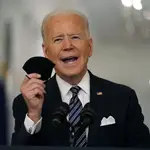 El presidente Joe Biden sostiene su mascarilla mientras habla sobre la pandemia de COVID-19