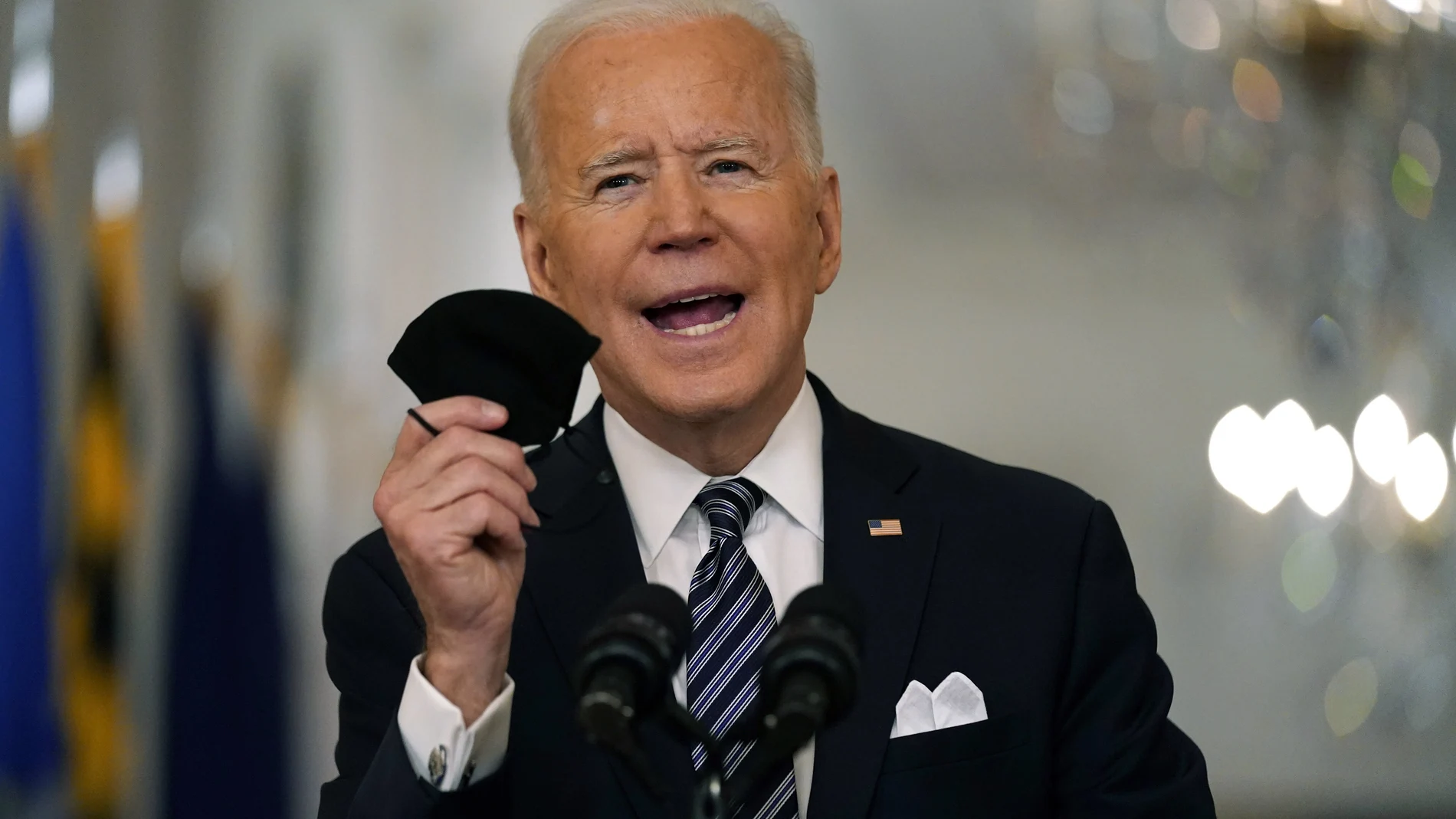 El presidente Joe Biden sostiene su mascarilla mientras habla sobre la pandemia de COVID-19