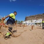 Dos operarios parcelan con cuerdas una playa en Mogán, en Gran Canaria