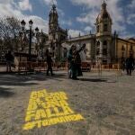 Transeúntes caminan al lado de una pintada que simboliza una de las demarcaciones falleras de la ciudad, en Valencia