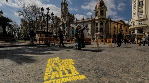 Transeúntes caminan al lado de una pintada que simboliza una de las demarcaciones falleras de la ciudad, en Valencia
