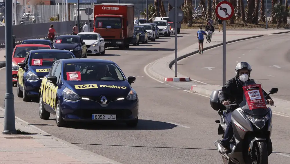 Marcha de la caravana de vehículos para denunciar la dejadez y falta de ayudas de las instituciones en el sector de la hostelería a su salida del Dique de Levante hacia el centro de la ciudad de Málaga