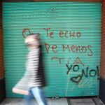 Una mujer pasa ante un grafiti en una calle del centro de Valencia