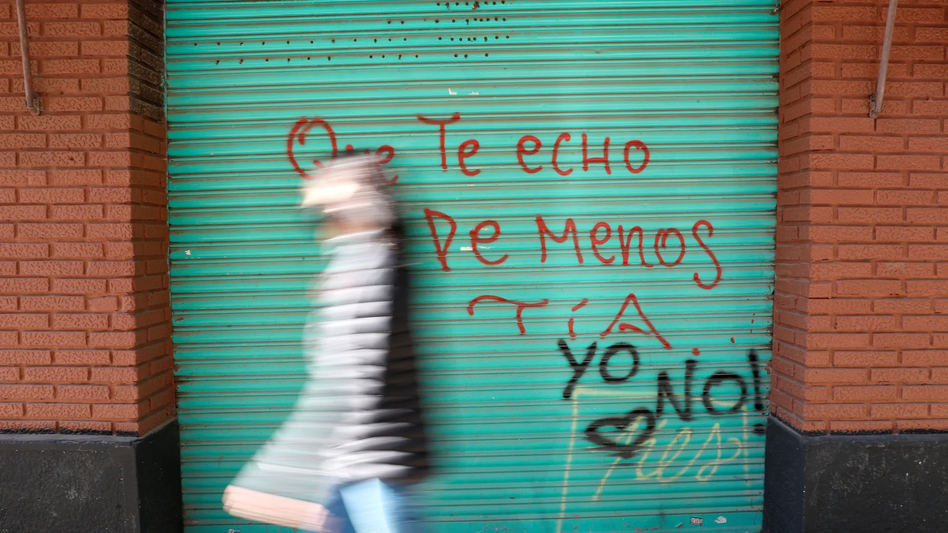 Una mujer pasa ante un grafiti en una calle del centro de Valencia