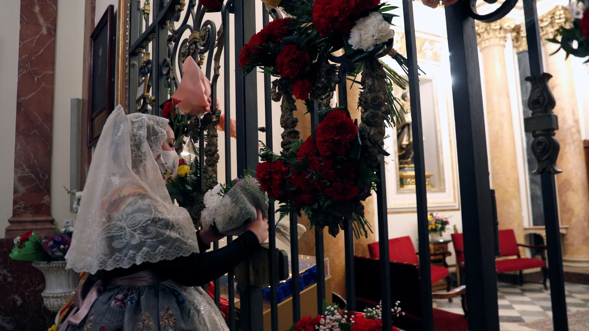 Una fallera deposita un ramo de flores frente a la Virgen
