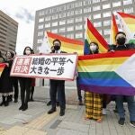 Los abogados y partidarios de los demandantes sostienen banderas de arcoíris y una pancarta que dice: "Sentencia inconstitucional"