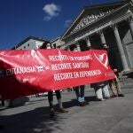 Varias personas sostienen una pancarta donde se puede leer "Recorte en pensiones, recorte sanitario, recorte en dependencia" durante una manifestación de Abogados Cristianos a las puertas del Congreso de los Diputados el 18 de marzo