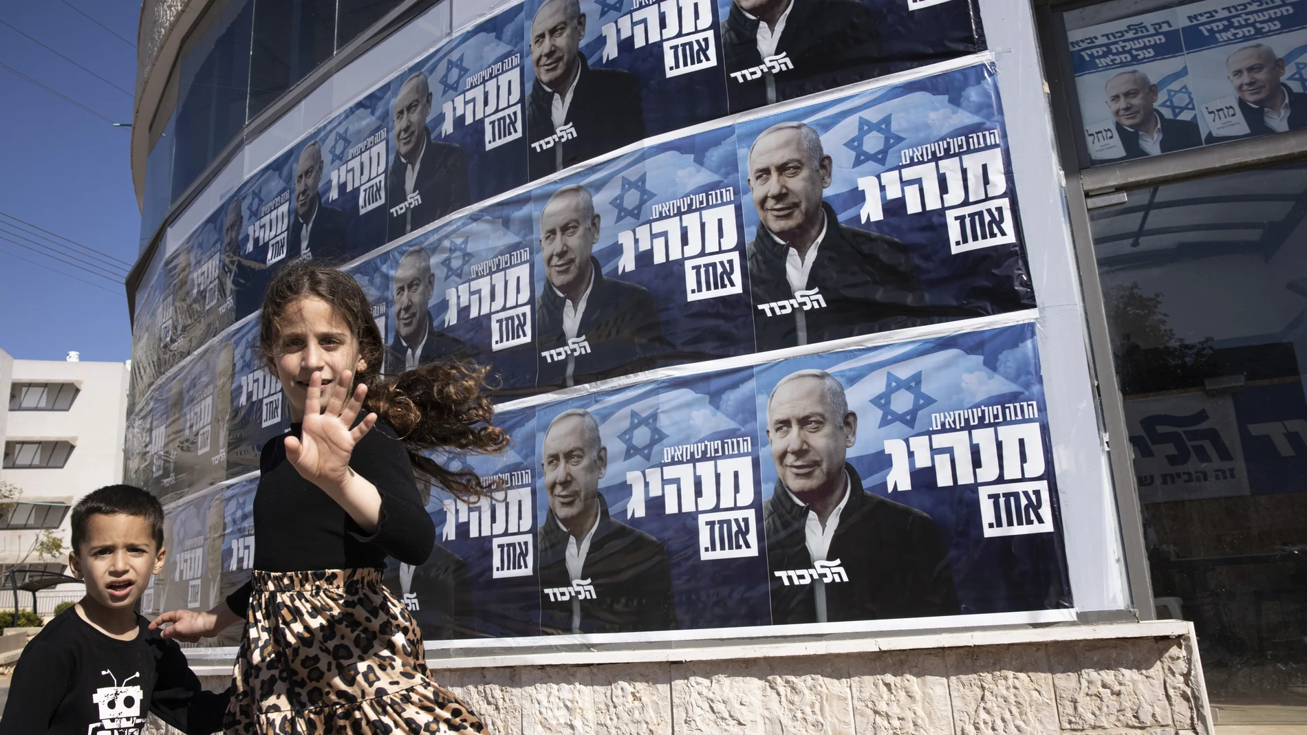 Niños israelíes caminan frente al cartel electoral del líder del Likud, Benjamín Netanyahu