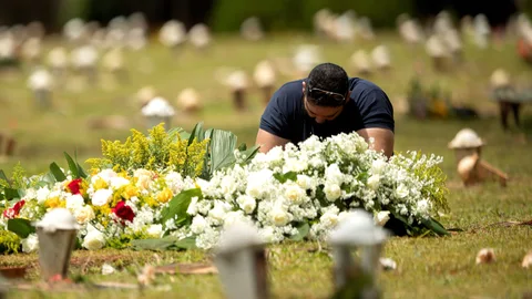 AME4755. BRASILIA (BRASIL), 23/03/2021.- Un hombre visita una tumba en el cementerio Campo de Esperanza, hoy, en Brasilia (Brasil). Brasil bordea los 300.000 muertos por covid-19, mientras persiste el riesgo de desabastecimiento de medicamentos esenciales para los enfermos con cuadros más graves ante el creciente número de hospitalizaciones. EFE/ Joédson Alves.