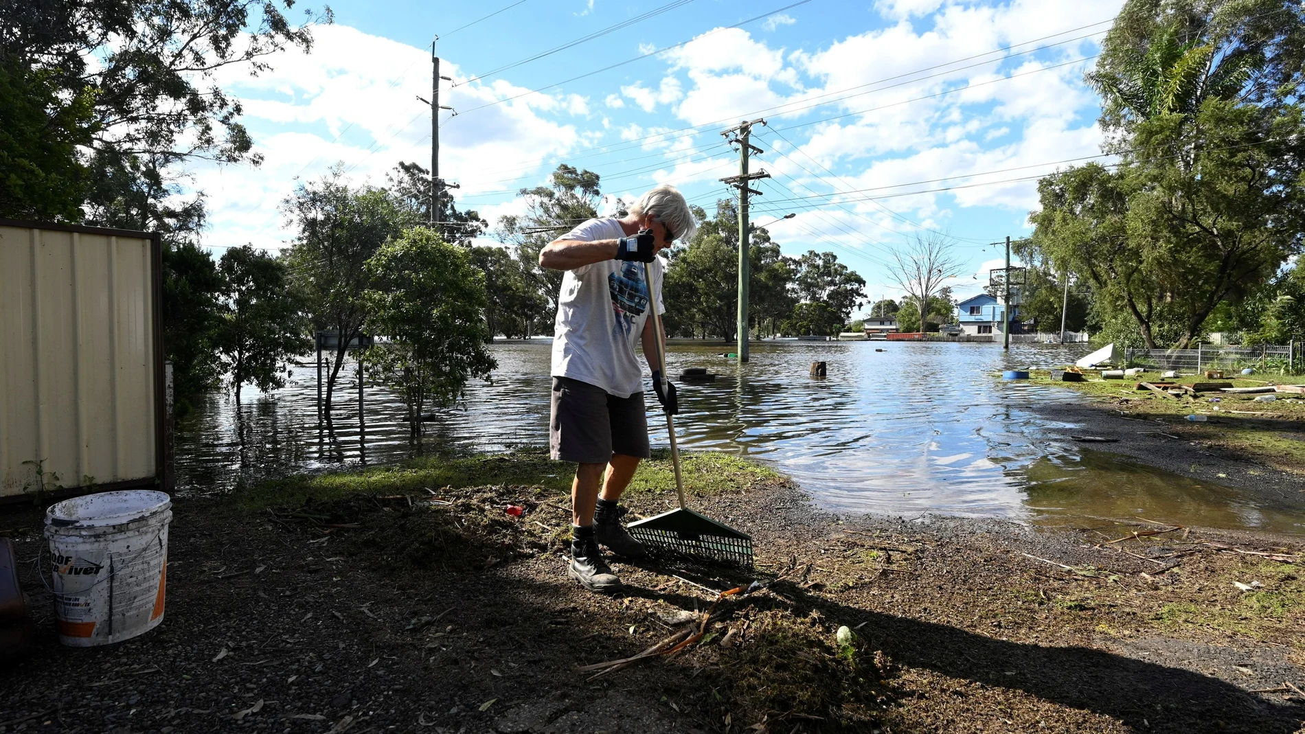 A man cleans up debris in front of his house in the suburb of Windsor as the state of New South Wales experiences widespread flooding and severe weather, near Sydney, Australia, March 24, 2021. REUTERS/Jaimi Joy