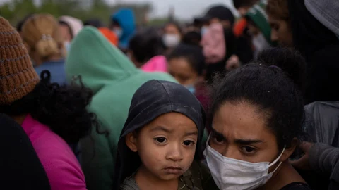 Keylin, una migrante hondureña en busca de asilo, sostiene a su hijo Olban, de tres años, en medio de docenas de otras personas mientras esperan subir a un autobús de la patrulla fronteriza