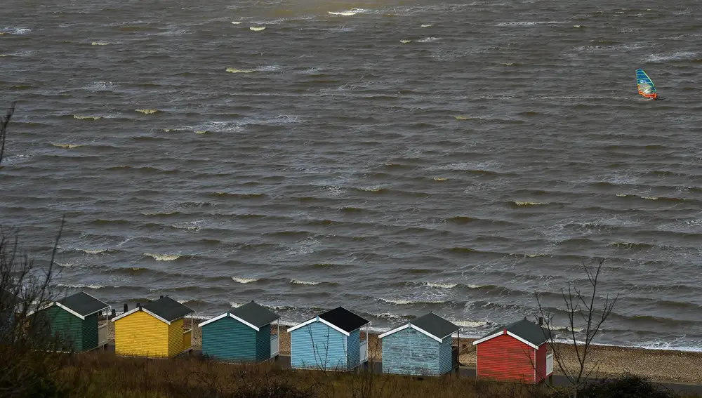 Un windsurfista y cabañas de playa se ven en Leysdown-on-Sea, en la isla de Sheppey