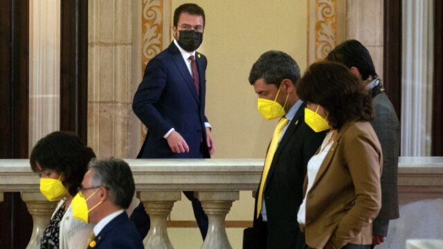 El candidato de ERC, Pere Aragonés, junto a varios diputados de JxCat, en los pasillos del Parlament.