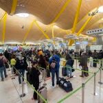 Pasajeros esperan para pasar los controles en la T4 del Aeropuerto Adolfo Suárez Madrid-Barajas, en Madrid