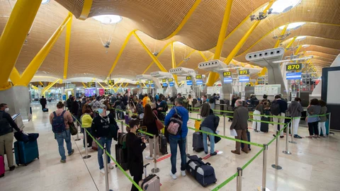 Pasajeros esperan para pasar los controles en la T4 del Aeropuerto Adolfo Suárez Madrid-Barajas, en Madrid