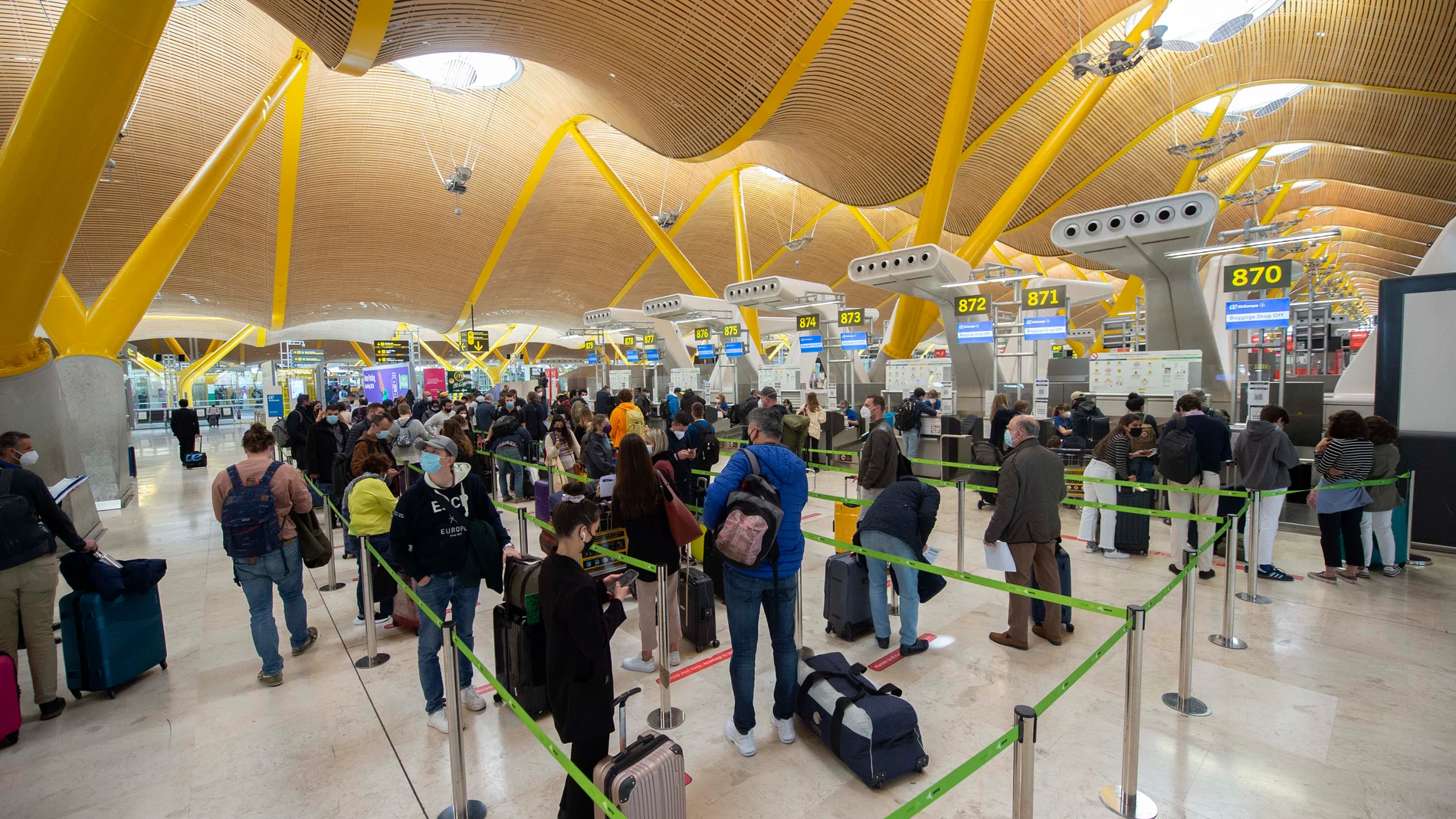 Pasajeros esperan para pasar los controles en la T4 del Aeropuerto Adolfo Suárez Madrid-Barajas, en Madrid