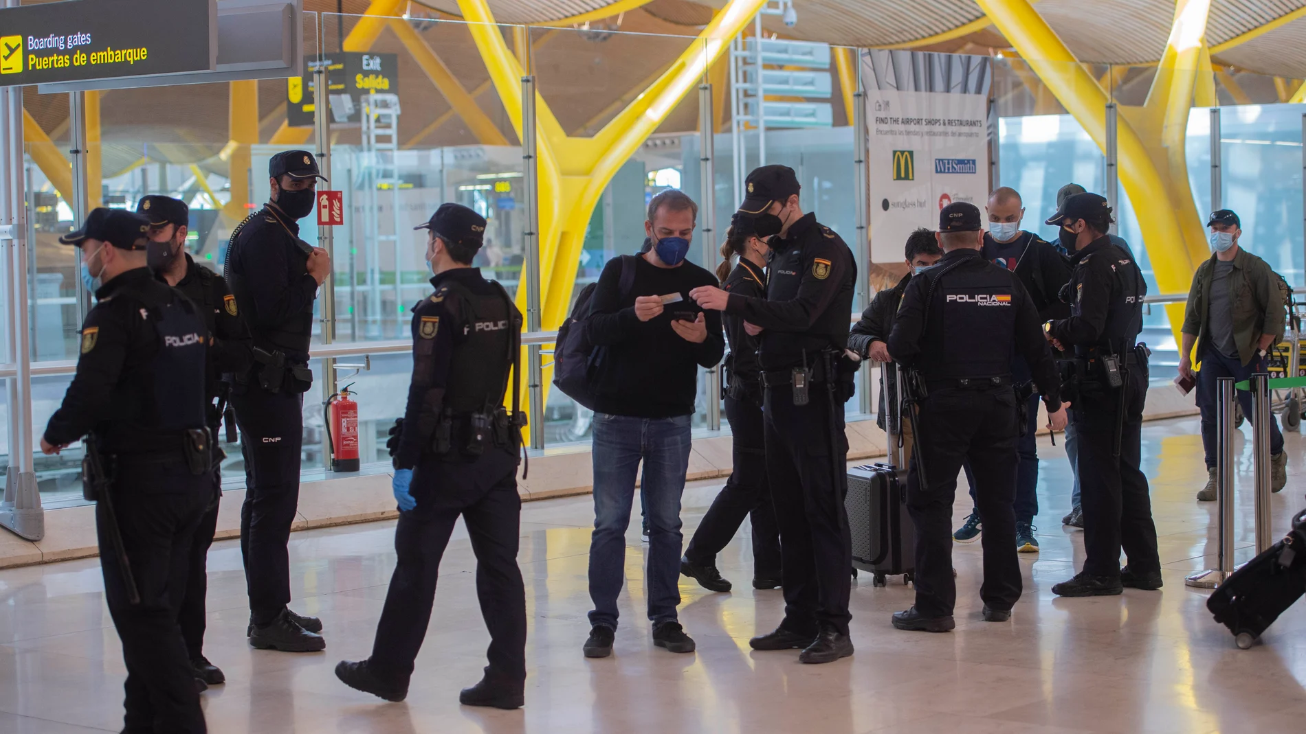 Agentes de policía nacional realizan controles a los pasajeros de la T4 del Aeropuerto Adolfo Suárez Madrid-Barajas, en Madrid