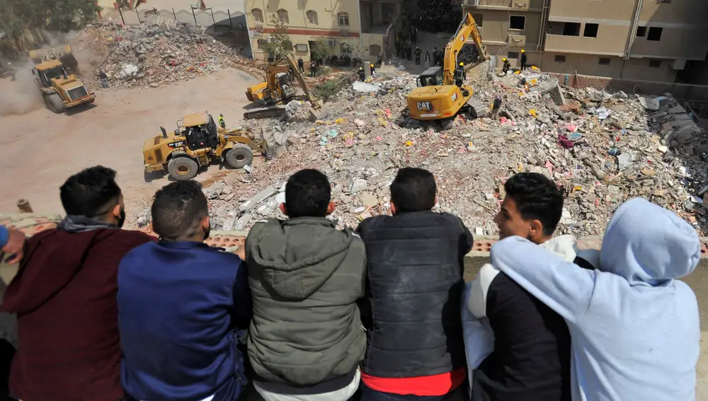 Unos jóvenes observan las tareas de rescate y desescombro en El Cairo