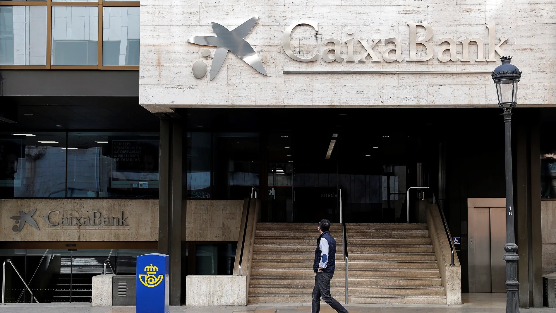 Un hombre observa el logo de Caixabank en la sede social en Valencia