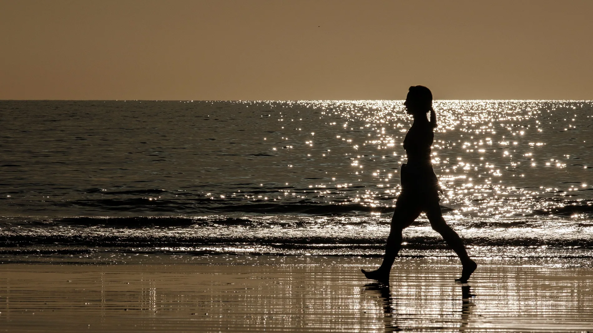Una mujer camina por la orilla de la playa de Maspalomas, en el sur de Gran Canaria.