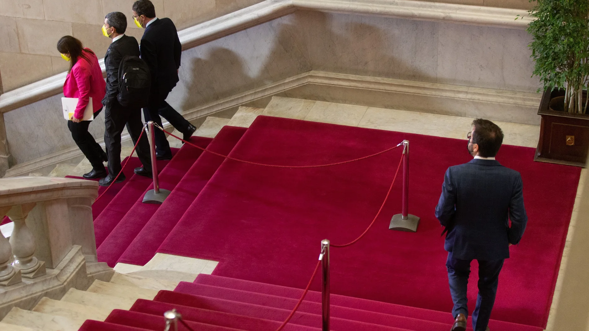 El candidato de ERC a la presidencia de la Generalitat, Pere Aragonès, baja las escaleras del Parlament detrás de los diputados de JxCat, Gemma Geis, Joan Canadell, y Josep Rius, durante un receso de la segunda sesión del debate de su investidura