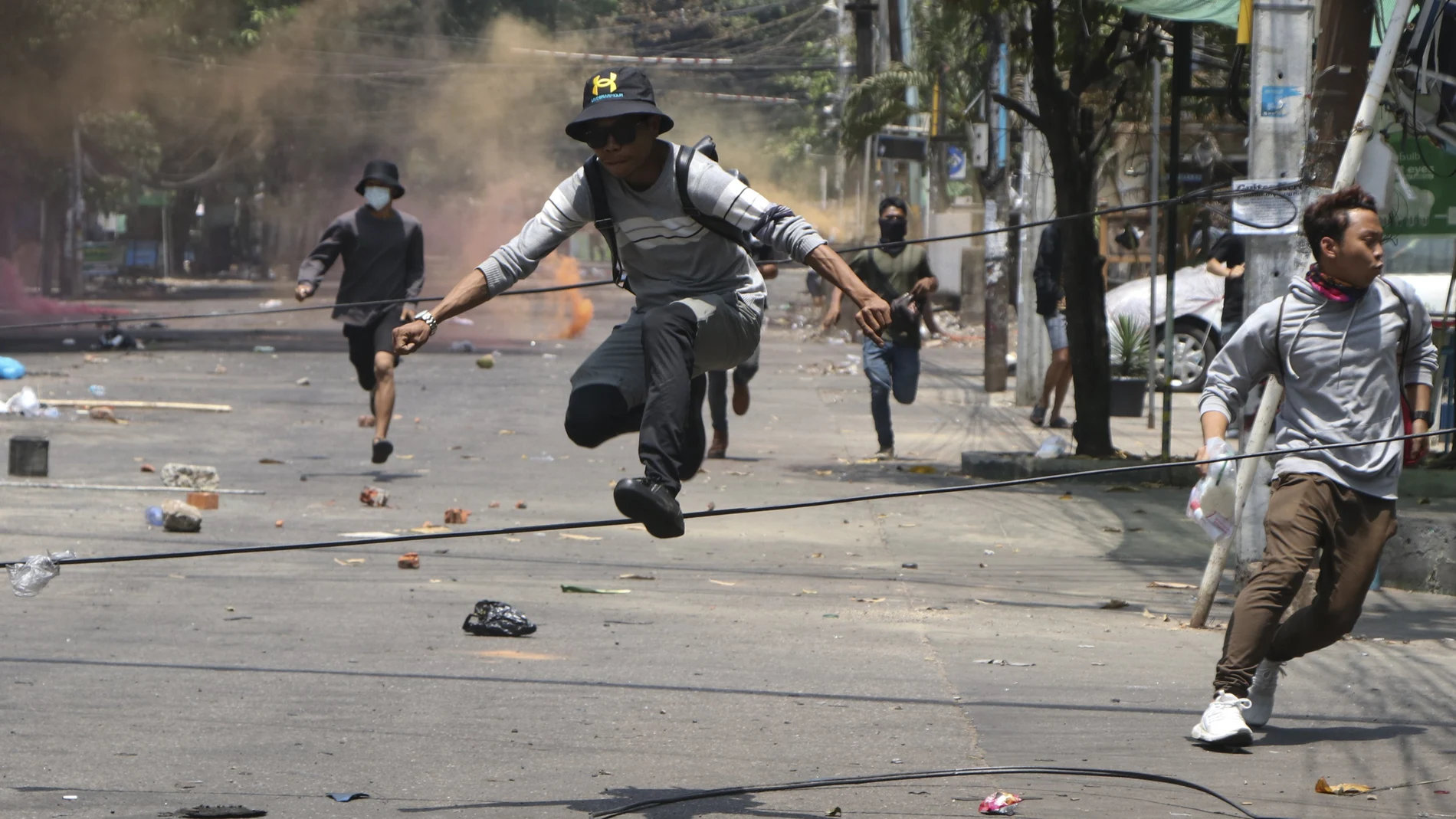 Varios jóvenes antigolpistas corren para huir de las Fuerzas Armadas, ayer, en Rangún