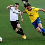 El delantero francés del Valencia Kevin Gameiro (i) trata de escapar de Juan Cala, del Cádiz, durante el partido de Liga en Primera División que disputan este domingo en el estadio Ramón de Carranza. EFE/Román Ríos