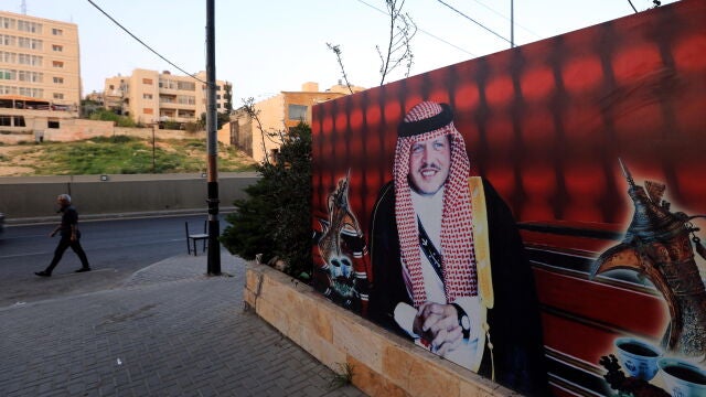 Un hombre camina por una calle de Amán junto a un cartel con la imagen del rey Abdalá de Jordania