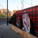 Un hombre camina por una calle de Amán junto a un cartel con la imagen del rey Abdalá de Jordania