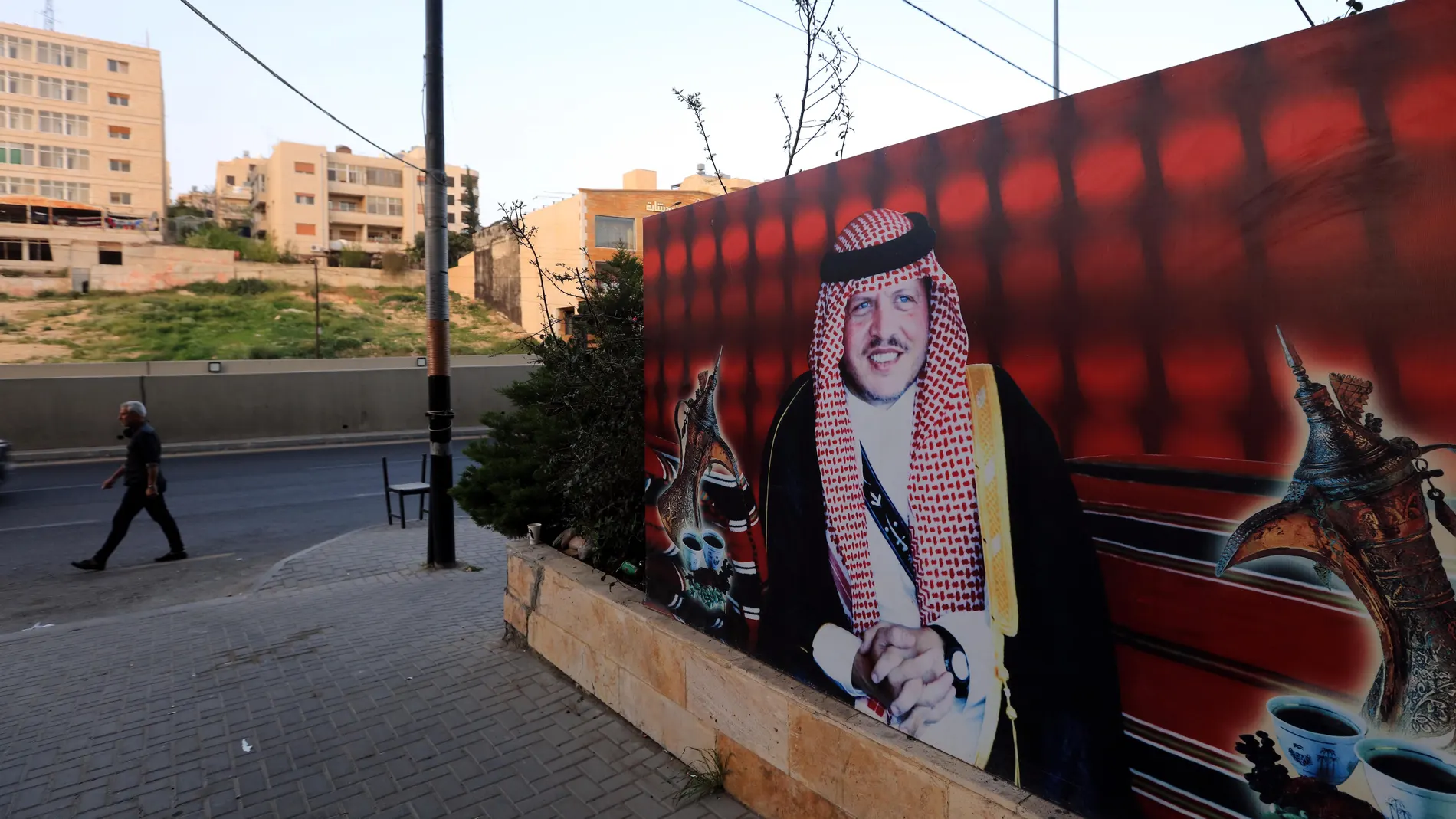 Un hombre camina por una calle de Amán junto a un cartel con la imagen del rey Abdalá de Jordania