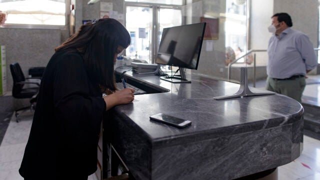 Una trabajadora en la recepción de un hotel atiende a un viajero