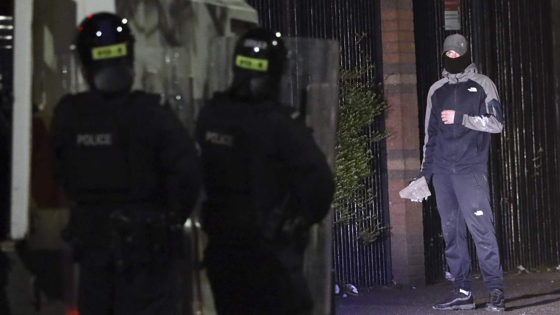 Un joven sostiene un objeto mientras mira a la Policía en un barrio unionista de Belfast el pasado viernes