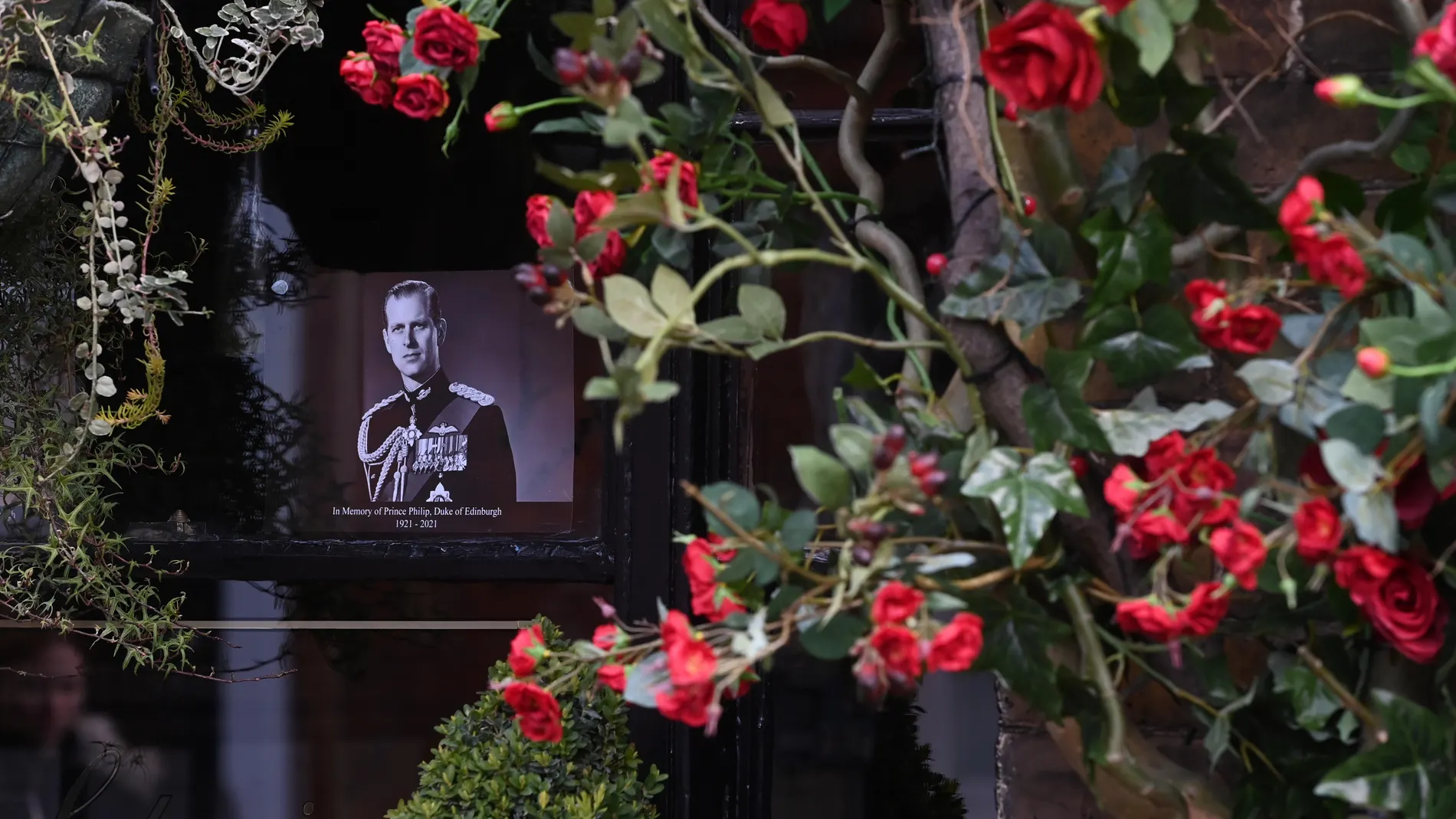 Una foto del duque de Edimburgo y flores en su honor en la ventana de un «pub» cercano al Castillo de Windsor