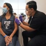 Jason Rodriguez, right, a University of Florida Pharmacy student, gives Camila Gutierrez, 21, a junior at Florida International University from Bolivia, the Pfizer COVID-19 vaccine at the Christine E. Lynn Rehabilitation Center in Jackson Memorial hospital, Thursday, April 15, 2021, in Miami. Jackson Health System launched a COVID-19 vaccination initiative with colleges and universities in Miami-Dade County, to allow students to sign up for vaccinations through an online portal. (AP Photo/Wilfredo Lee)